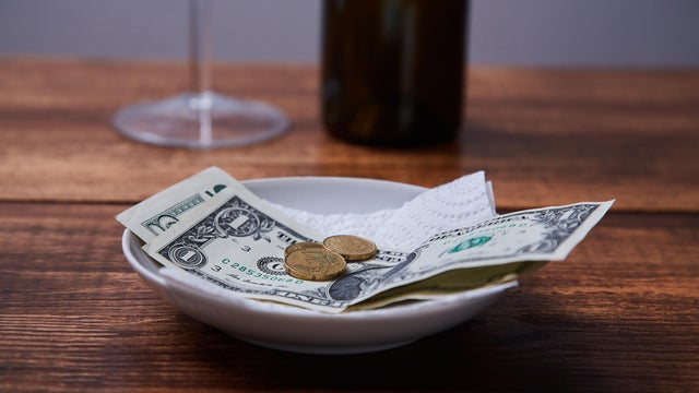Restaurant tips or gratuity. Banknotes and coins on a plate 
