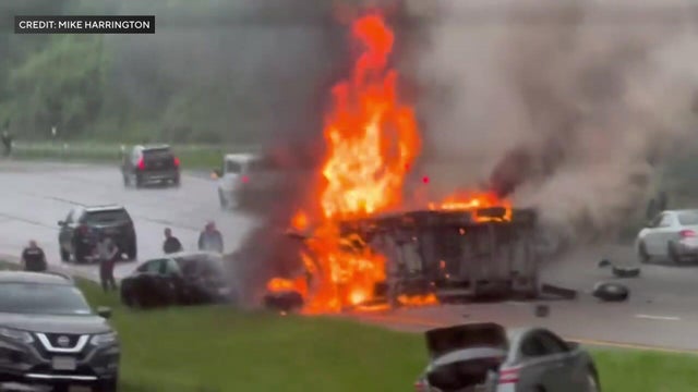 A van on its side on fire on the parkway. 